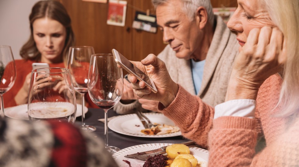 group of people using smartphones at dinner